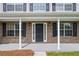 Close-up of the brick front porch, showcasing the entrance door, white columns, and classic exterior lighting at 6895 Smoke Ridge Dr, Atlanta, GA 30349