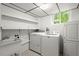 Bright laundry room with a sink, shelving, washer, dryer, and storage cabinets at 1000 Grimes Bridge Rd, Roswell, GA 30075