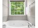 A relaxing soaking tub with a large bright window and tile surround offers great views at 220 Finchley Dr, Roswell, GA 30076