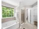 Bright bathroom features a soaking tub under a large window, plus a separate glass-enclosed shower at 220 Finchley Dr, Roswell, GA 30076