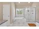 Bright bathroom featuring a soaking tub and frameless glass shower, surrounded with marble tile at 2767 Camp Mitchell Rd, Loganville, GA 30052