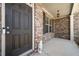 Close-up of a covered front porch with brick facade and a decorative front door at 5465 Mirror Lake Dr, Cumming, GA 30028