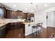 Kitchen features dark wood cabinets, stainless steel appliances, granite countertops, and an island with bar seating at 5465 Mirror Lake Dr, Cumming, GA 30028