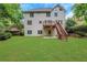 Expansive backyard featuring lush green lawn, mature trees, and wooden stairs leading to a deck at 5435 Vicarage Walk, Alpharetta, GA 30005