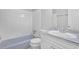 Well-lit bathroom featuring a tub with white tile surround, a sink, and white cabinets at 6307 Thornhedge Dr, Riverdale, GA 30296