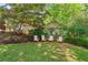 Well-manicured backyard with lush grass, mature trees, and a cozy seating area with pink Adirondack chairs at 1028 Amsterdam Ne Ave, Atlanta, GA 30306