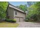 View of the rear exterior featuring a two-car garage, siding, and mature trees at 3335 New Heritage Dr, Alpharetta, GA 30022