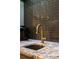 Close up of a golden faucet on a granite countertop with a tile backsplash in a bar area at 9950 Farmbrook Ln, Johns Creek, GA 30022