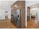 Spacious kitchen with wood floors and stainless steel fridge, adjacent to hallway and office at 9950 Farmbrook Ln, Johns Creek, GA 30022