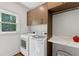 Bright laundry room features a modern washer and dryer, wooden cabinets, and a large window offering natural light at 9950 Farmbrook Ln, Johns Creek, GA 30022