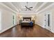 Bright bedroom with hardwood floors, a tray ceiling, shutters, and a comfortable bed at 9950 Farmbrook Ln, Johns Creek, GA 30022