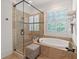 Elegant bathroom featuring a soaking tub, a glass-enclosed shower, and a linen closet at 11660 Crabapple Rd, Roswell, GA 30075