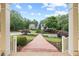 View of the elegant home with mature landscaping and a brick walkway at 11660 Crabapple Rd, Roswell, GA 30075