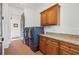 Well-lit laundry room with brick flooring, blue washer/dryer and wood cabinets with granite countertop at 11660 Crabapple Rd, Roswell, GA 30075