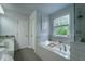 Well-lit bathroom features a tiled tub, separate glass shower, and natural light at 155 Marlow Dr, Woodstock, GA 30188