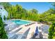 Community pool area with lounge chairs, tables, and umbrellas, surrounded by lush greenery at 155 Marlow Dr, Woodstock, GA 30188