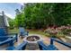 Cozy backyard fire pit area with blue Adirondack chairs and mature trees for relaxed outdoor living at 155 Marlow Dr, Woodstock, GA 30188