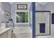 Bathroom with a bathtub, shower, blue accent wall, and leafy outdoor views at 529 Wintergreen Way, Canton, GA 30115