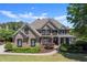 Elegant brick home with manicured lawn, lush landscaping, and a welcoming covered front porch at 146 Cedar Woods Trl, Canton, GA 30114
