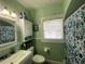 Bathroom boasts a vanity, shower with curtain, overhead storage, and a window for natural light at 212 South Se Ave, Marietta, GA 30060