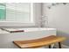 Stylish soaking tub with wooden stool and faucet fixtures by window with blinds at 1436 Belmont Ave, Smyrna, GA 30080
