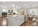 Open-concept kitchen with stainless steel appliances, granite counters, farmhouse sink, and adjacent living and dining areas at 1436 Belmont Ave, Smyrna, GA 30080