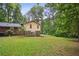 Large grassy backyard with brick patio and mature trees behind a two story home at 358 W West Wind Sw Dr, Lilburn, GA 30047