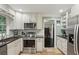 Well-equipped kitchen with stainless steel appliances, white cabinets, subway tile backsplash, and dark countertops at 358 W West Wind Sw Dr, Lilburn, GA 30047