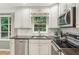 Well-equipped kitchen with stainless steel appliances, white cabinets, subway tile backsplash, and dark countertops at 358 W West Wind Sw Dr, Lilburn, GA 30047