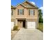 Charming two-story townhome with beige siding, brick accents, and a single-car garage at 6001 Oak Bend Ct, Riverdale, GA 30296