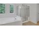 Bright bathroom featuring a soaking tub, glass-enclosed shower, and natural light from adjacent windows at 3208 Juniper Nw Dr, Kennesaw, GA 30144