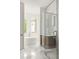 Bright bathroom showcasing a freestanding tub, glass-enclosed shower, and marble flooring at 11542 Serenbe Ln, Chattahoochee Hills, GA 30268