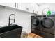 Modern laundry room with dark front loading washer and dryer, black sink and matte black fixtures at 4439 Luther Ward Rd, Powder Springs, GA 30127