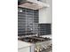 Close up of a gourmet stainless steel range top and backsplash featuring modern black subway tile at 2335 Mason Dr # D27, Atlanta, GA 30316