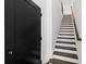 Staircase with dark wood treads and white risers, next to a sleek black door at 2335 Mason Dr # D27, Atlanta, GA 30316