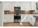 Well-lit kitchen showcasing white cabinets, stainless steel appliances, and designer tile backsplash at 2934 Wendover St, Marietta, GA 30062