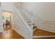 Elegant staircase with white banister and wood treads, complemented by dining room and hardwood floors at 303 Cimarron Way, Lawrenceville, GA 30044