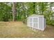 A storage shed with white trim sits on the lawn in a wooded back yard at 303 Cimarron Way, Lawrenceville, GA 30044