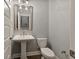 Compact powder room with a pedestal sink, toilet, and decorative light fixture at 4382 Benfield Se Way, Smyrna, GA 30080