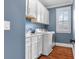 Modern laundry room with shaker cabinets, window with shutters, sink, and washer-dryer at 686 Amsterdam Ne Ave, Atlanta, GA 30306