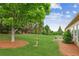 Large grassy backyard with a mature shade tree and patio seating near the house at 1815 Montcliff Dr, Cumming, GA 30041