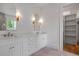 Bright bathroom with double vanity, marble countertop, decorative mirrors, sconces, and doorway to closet at 50 Maple St, Roswell, GA 30075