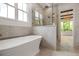 Luxurious bathroom features a soaking tub, walk-in shower, tile surround, and stunning outdoor views at 50 Maple St, Roswell, GA 30075