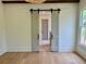 Bedroom view featuring natural light, an elegant light fixture, and a sliding barn door to the ensuite bathroom at 50 Maple St, Roswell, GA 30075