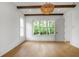 A bright bedroom with a beamed ceiling featuring hardwood floors and large windows offering scenic views at 50 Maple St, Roswell, GA 30075
