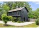Modern two-story home featuring dark siding, manicured lawn, concrete driveway and green landscaping at 2824 Tupelo Se St, Atlanta, GA 30317