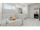 This bright bathroom features a double vanity, a large mirror, white cabinets, a separate tub, and tiled floors at 485 St Annes Pl, Covington, GA 30016