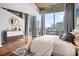 Bedroom with hardwood floors, modern dresser and bed, with large windows and city views at 860 Peachtree Ne St # 909, Atlanta, GA 30308