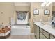 Bright bathroom featuring a large soaking tub, vanity with solid surface countertops at 3125 Flatbottom Dr, Dacula, GA 30019