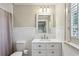 Bathroom featuring white vanity, white tile, a framed mirror, and window with privacy blinds at 4627 Angelo Ne Dr, Atlanta, GA 30319